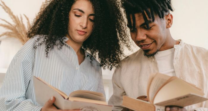 a lighter skinned woman with curly hair and a brown skinned man with locs reading books together.jpg.optimal