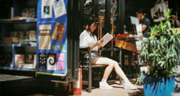 Asian woman reading outside bookstore.jpeg.optimal