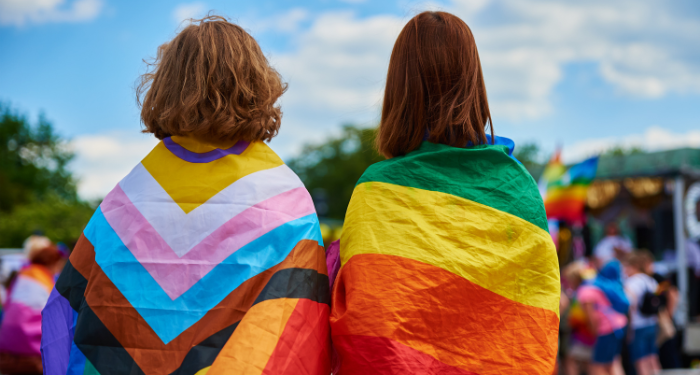 two young people wearing pride flags